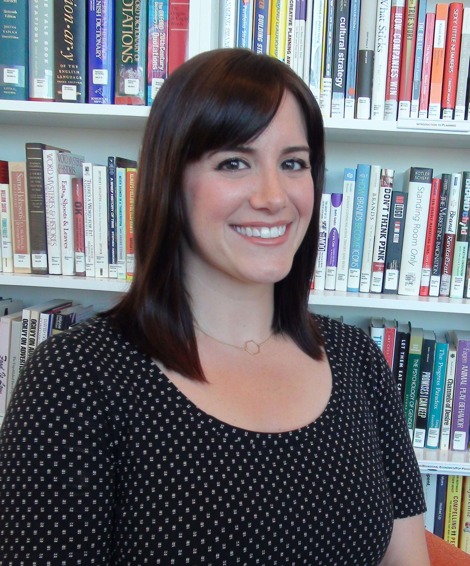 Woman with a black and white polka-dot tshirt standing in front of a bookshelf