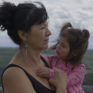 A woman and a little girl standing outside looking at something beyond the camera