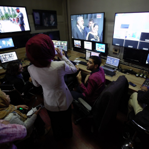 A woman talking to a man in a television show control room.