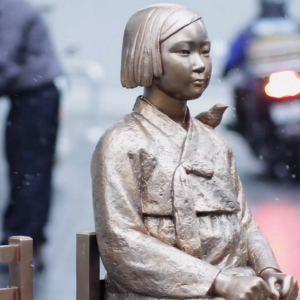 THE SPACE WE HOLD Bronze statue of a young asian girl sitting on a chair in the middle of a sidewalk