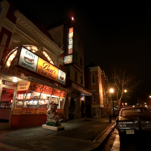 Image of a dark night street with bright shop signs
