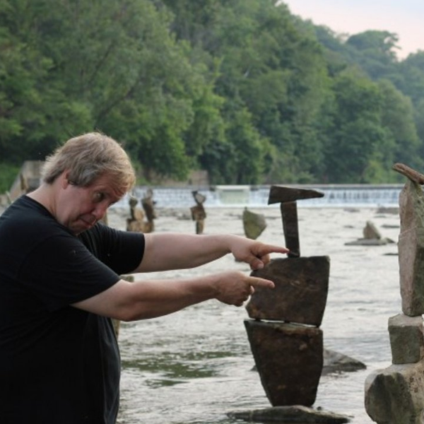 Image of a man standing by water pointing at rocks.