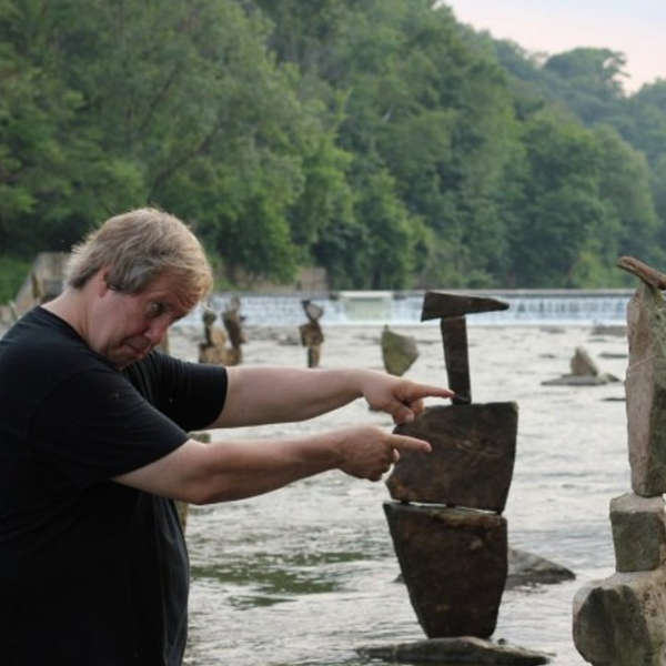 15 REASONS TO LIVE Image of a man standing by water pointing at rocks.