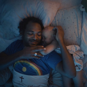 Photo of a man in bed with a young child who is ill.