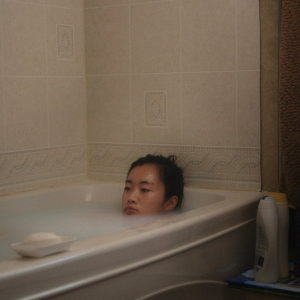 Hazy photo of a young girl laying in a bathtub with the water up to her mouth