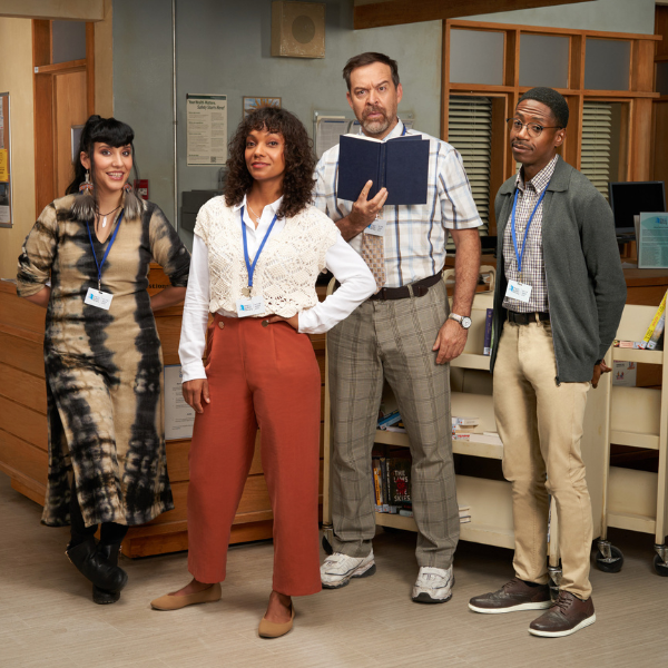 Four teachers, two female, two male stand in the offices of a school