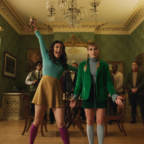 HOMESCHOOLED Two young girls standing in a foyer of an older looking home. One looks distressed while the other is jumping for joy.