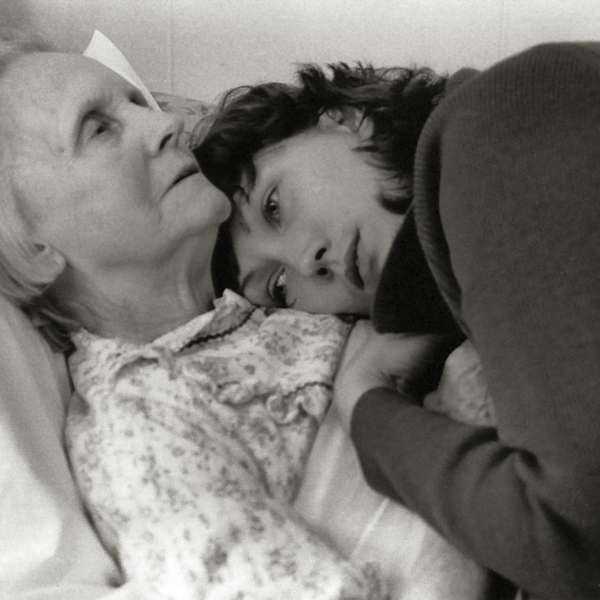 Black and white image of a young girl laying down and hugging and older lady